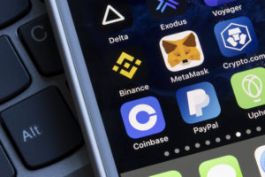 a smartphone with several apps like Coinbase and Binance shown on the home screen