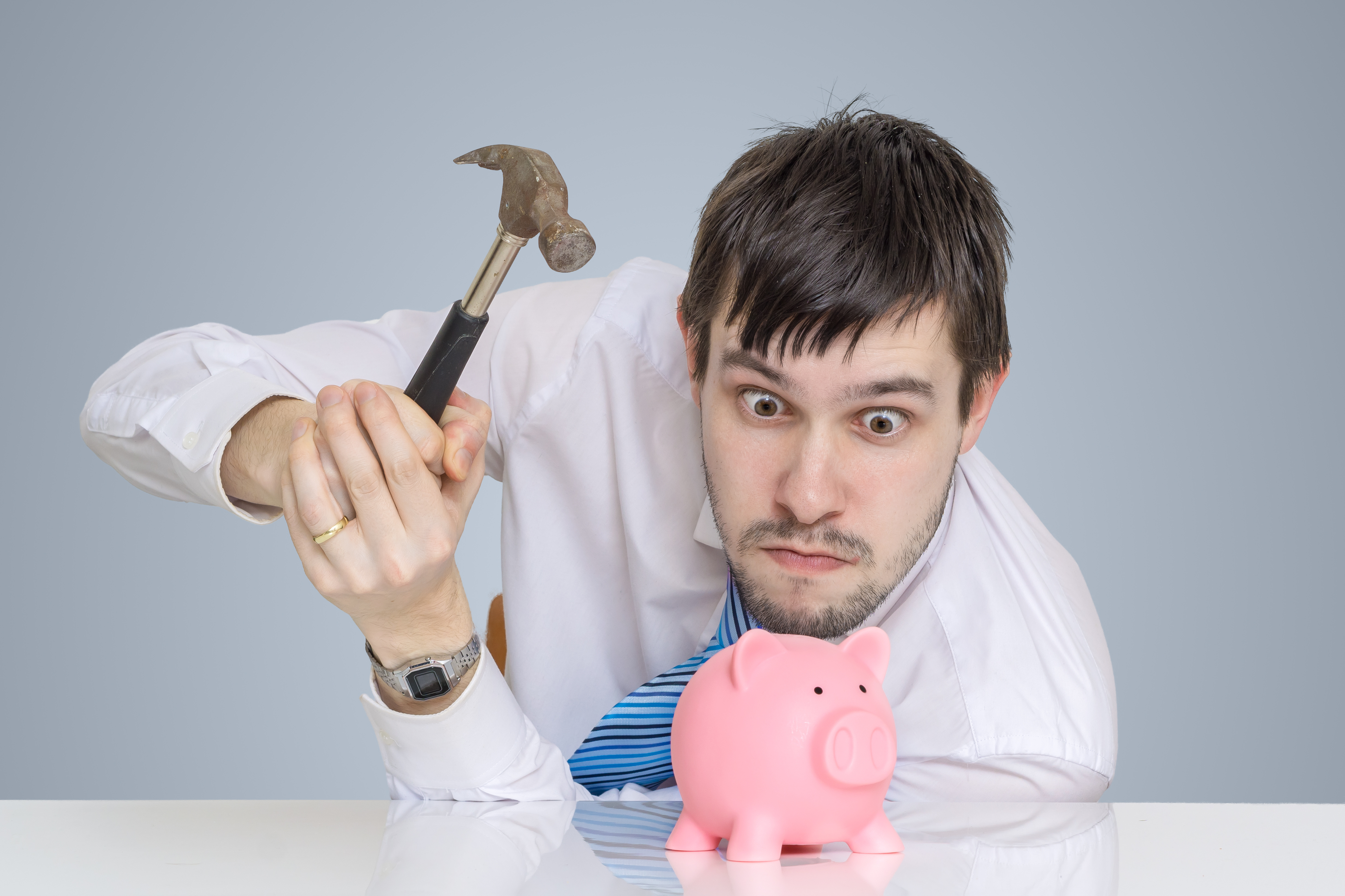 Young man is breaking piggy money bank with hammer to take his s
