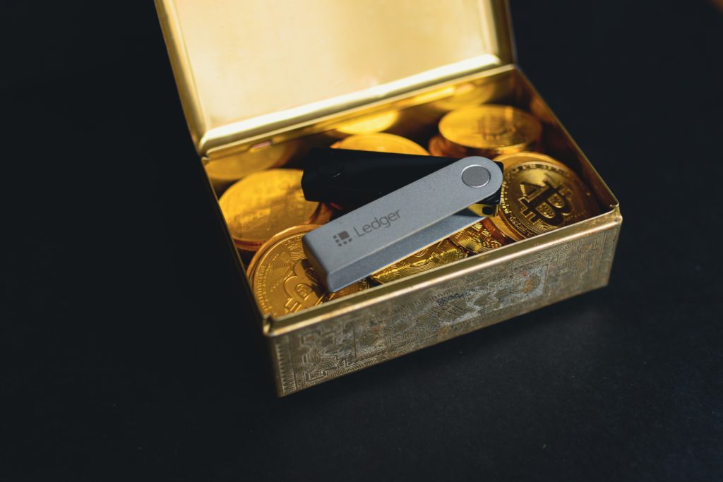 Ledger crypto wallet in gold box with Bitcoin tokens