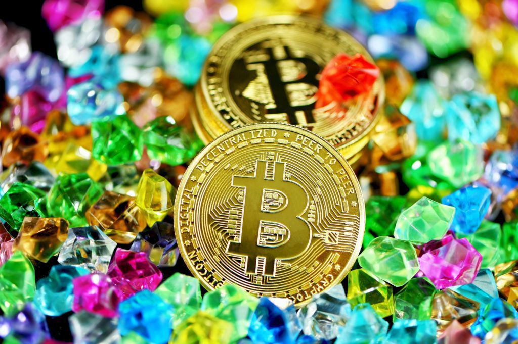 Bitcoin tokens on pile of colorful gems