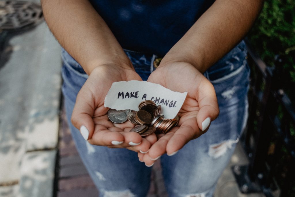 Hands holding coins and a scrap of paper saying "make a change"